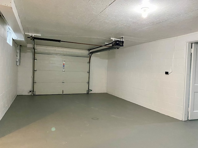 garage with a garage door opener and concrete block wall