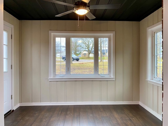 unfurnished room featuring dark wood finished floors, a healthy amount of sunlight, baseboards, and ceiling fan