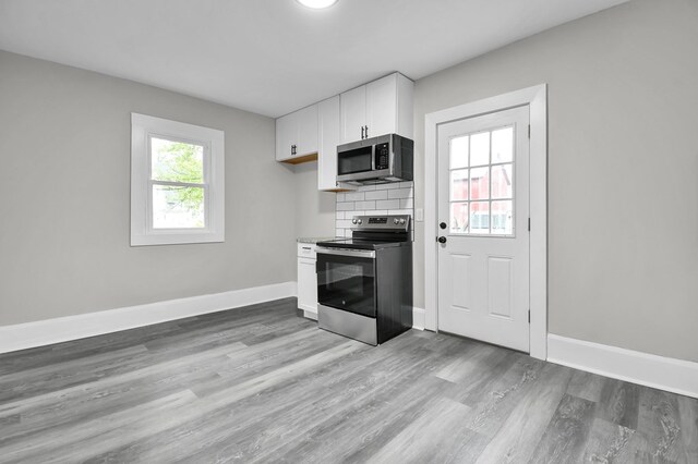 44 W 4th St, Fredericktown, OH 43019 - kitchen with appliances with stainless steel finishes, white cabinets, light wood-style flooring, and backsplash