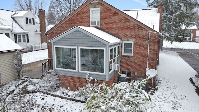 snow covered house featuring cooling unit