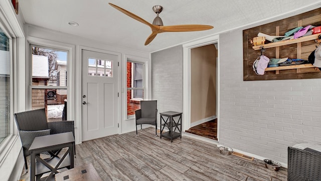 interior space with ceiling fan, light hardwood / wood-style floors, crown molding, and brick wall