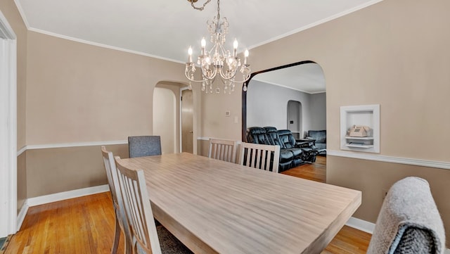 dining room with hardwood / wood-style floors, a notable chandelier, and ornamental molding