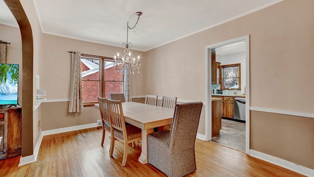 dining area featuring crown molding, light hardwood / wood-style flooring, and an inviting chandelier