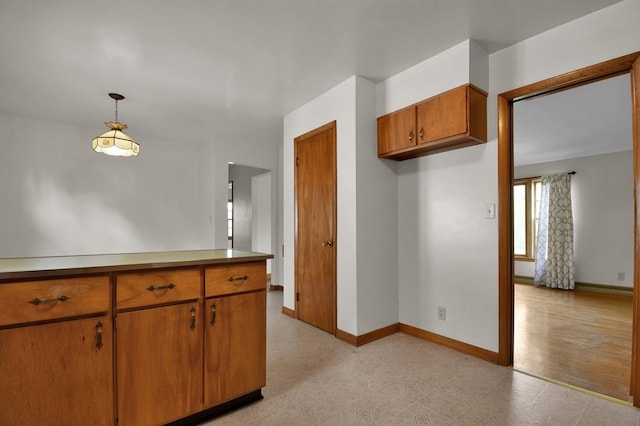 kitchen with light countertops, brown cabinets, baseboards, and pendant lighting