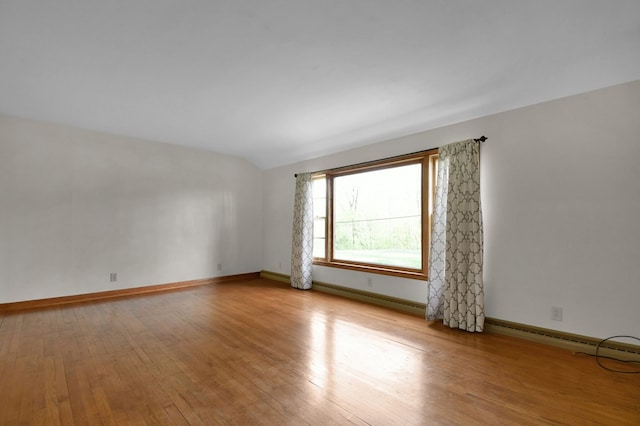 empty room featuring vaulted ceiling, a baseboard radiator, baseboards, and wood finished floors