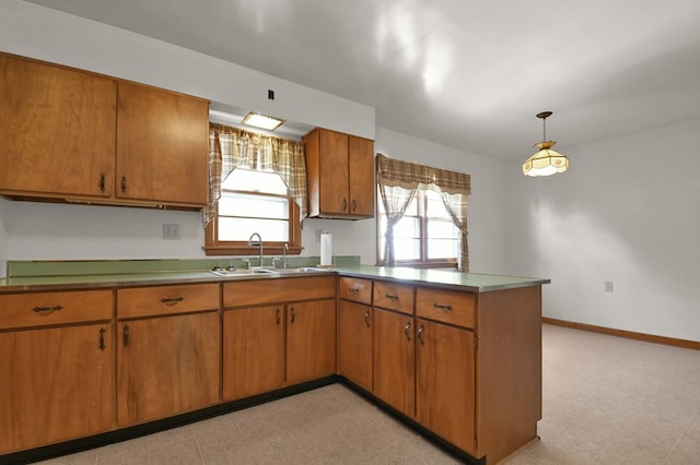 kitchen with a peninsula, a wealth of natural light, brown cabinets, and a sink
