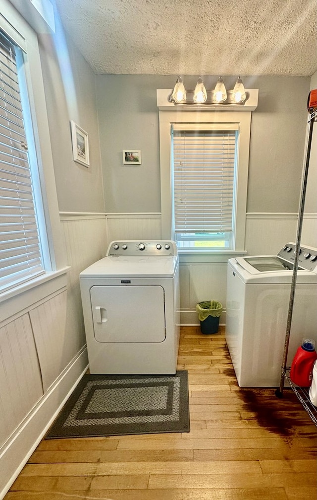 washroom with washer and dryer, a textured ceiling, and light hardwood / wood-style flooring