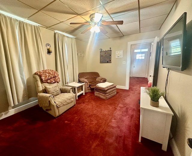 sitting room featuring a paneled ceiling, ceiling fan, and carpet