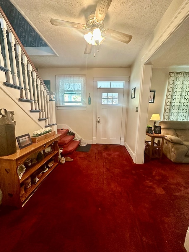 doorway featuring carpet flooring, ceiling fan, and a textured ceiling