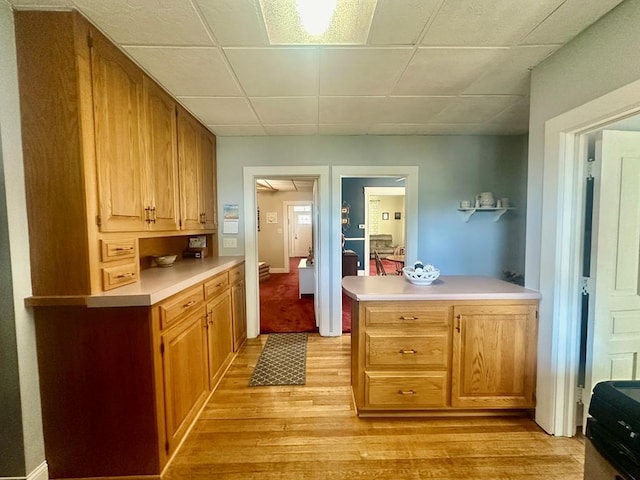 kitchen featuring kitchen peninsula, light wood-type flooring, and a drop ceiling