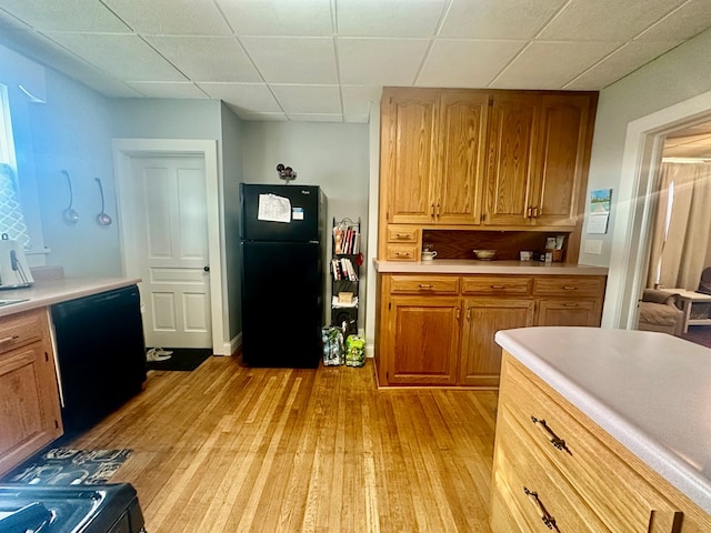 kitchen featuring black appliances, a drop ceiling, and light hardwood / wood-style floors