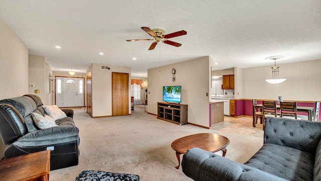 living room with ceiling fan, a textured ceiling, and light carpet