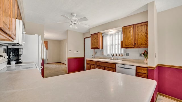 kitchen with kitchen peninsula, decorative backsplash, white appliances, ceiling fan, and sink