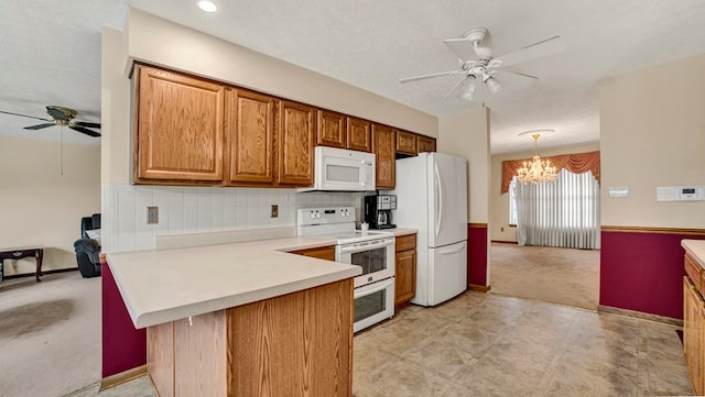 kitchen featuring white appliances, backsplash, ceiling fan with notable chandelier, decorative light fixtures, and kitchen peninsula