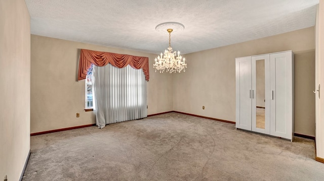 unfurnished room with a chandelier, a textured ceiling, and light colored carpet