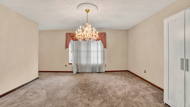 empty room featuring a textured ceiling, a notable chandelier, and light carpet