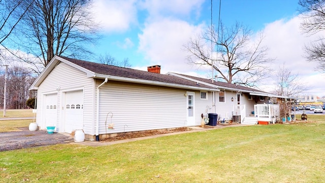 rear view of house with a garage, a yard, and central AC unit