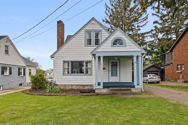view of front of home with a porch, a front yard, and a chimney