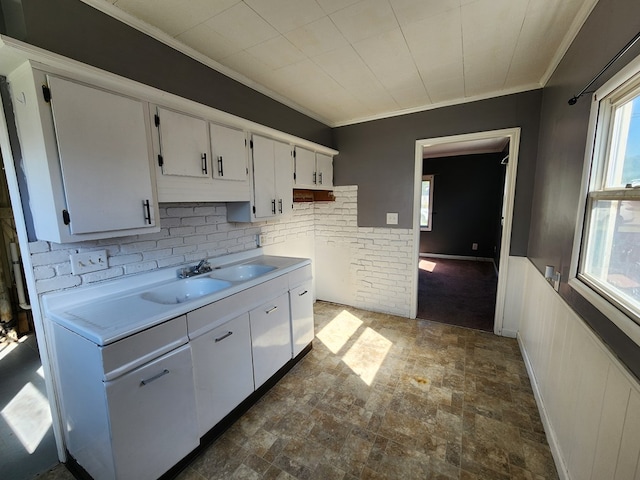 kitchen featuring white cabinetry, ornamental molding, and sink