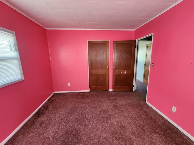 empty room with dark colored carpet and crown molding