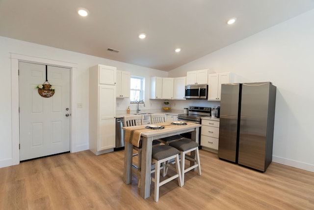 kitchen with stainless steel appliances, light countertops, light wood-style floors, white cabinetry, and a sink