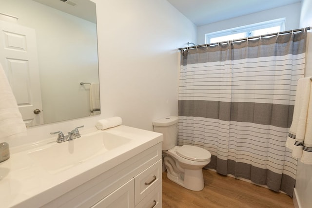 bathroom featuring curtained shower, visible vents, toilet, vanity, and wood finished floors