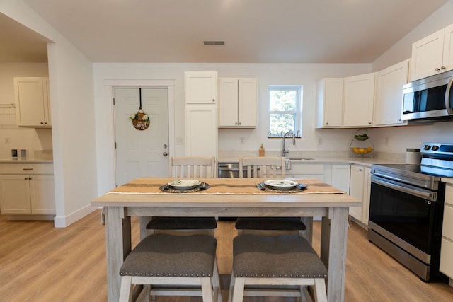 kitchen featuring stainless steel appliances, light wood-type flooring, a sink, and visible vents