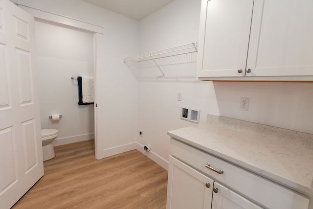 clothes washing area with cabinet space, baseboards, hookup for a washing machine, hookup for an electric dryer, and light wood-type flooring