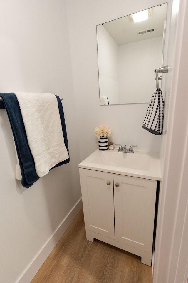 bathroom featuring vanity, wood finished floors, visible vents, and baseboards