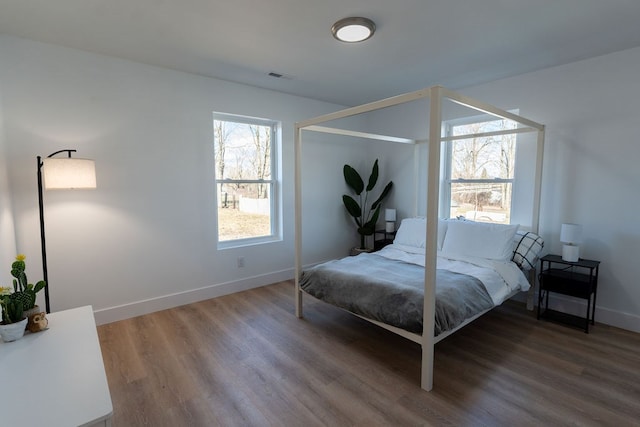 bedroom featuring baseboards, visible vents, and wood finished floors