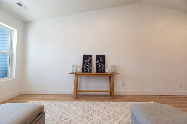 unfurnished room featuring light wood-type flooring, visible vents, vaulted ceiling, and baseboards