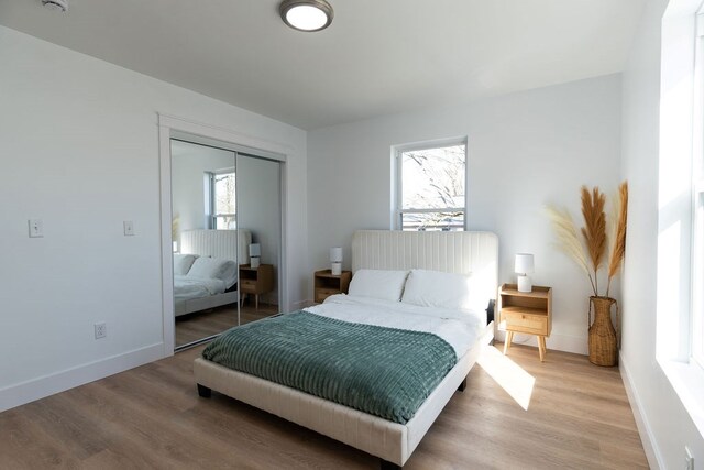 bedroom featuring a closet, light wood-style flooring, and baseboards