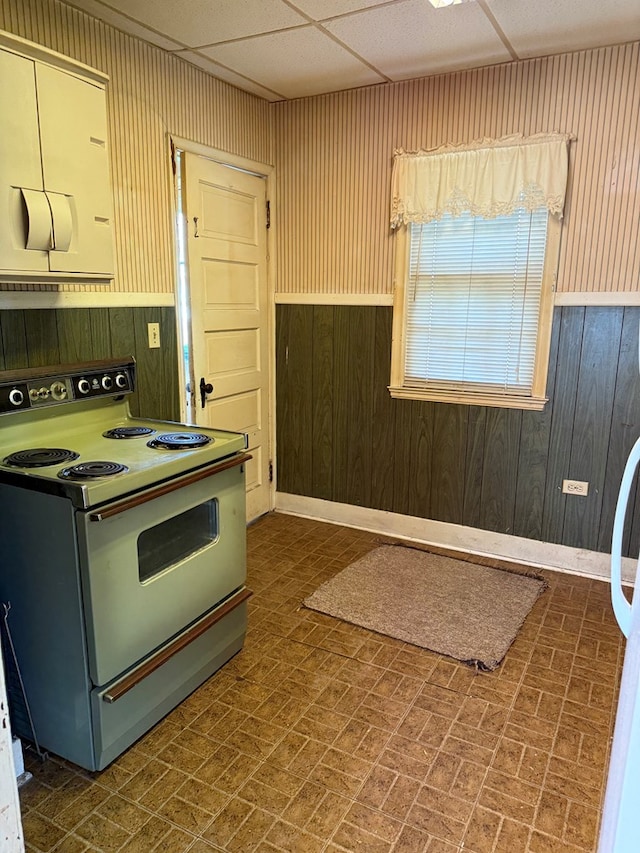 kitchen with a wainscoted wall, wooden walls, brick patterned floor, and white range with electric stovetop