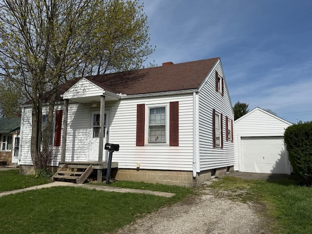 bungalow featuring a detached garage, a chimney, dirt driveway, an outbuilding, and roof with shingles