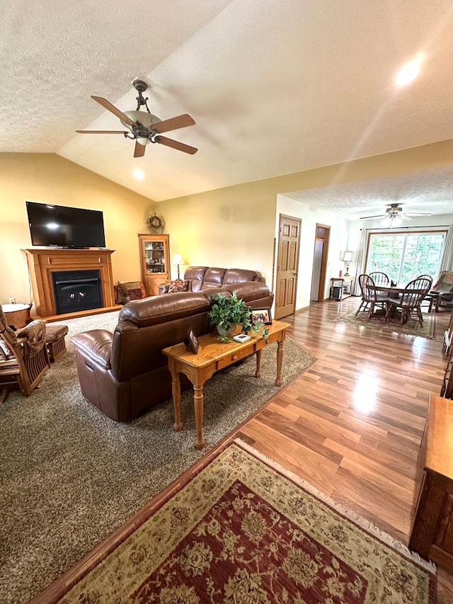 living room featuring vaulted ceiling, ceiling fan, hardwood / wood-style floors, and a textured ceiling