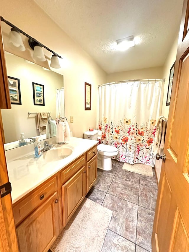 bathroom with vanity, toilet, and a textured ceiling