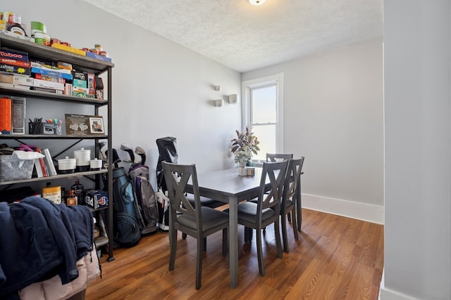 dining area featuring baseboards, a textured ceiling, and wood finished floors
