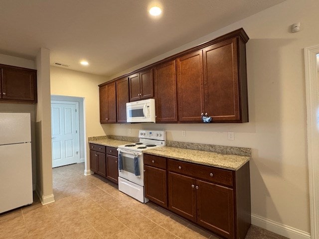 kitchen featuring dark brown cabinetry, light tile patterned flooring, and white appliances