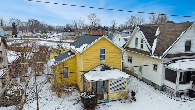 snow covered rear of property with a sunroom