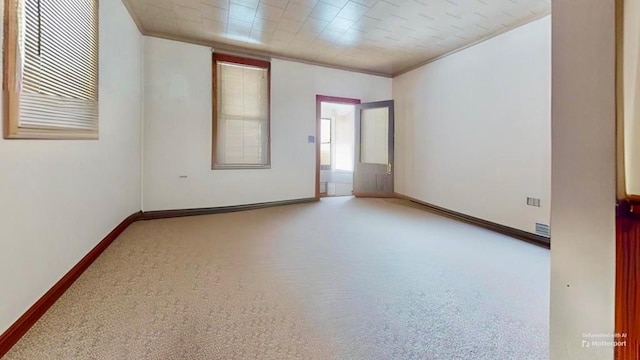 empty room featuring crown molding and light carpet