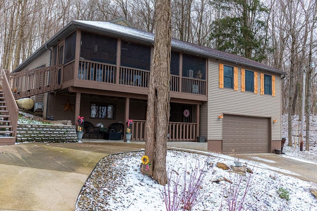 chalet / cabin featuring a garage, a sunroom, driveway, stairway, and a patio area