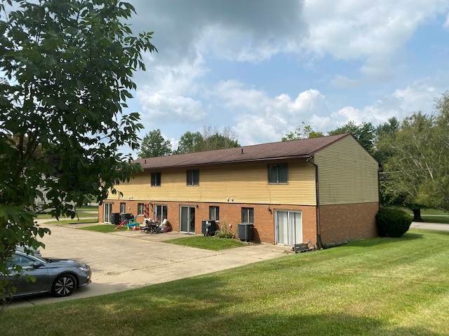 back of property featuring cooling unit and a yard