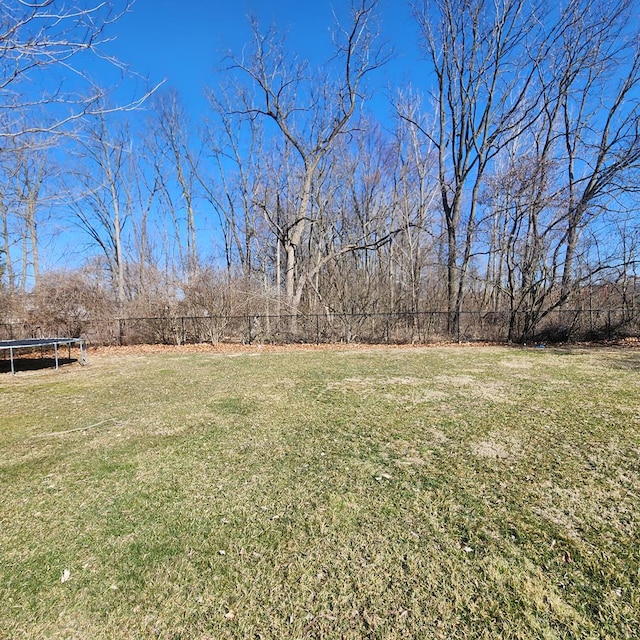 view of yard featuring a trampoline and fence