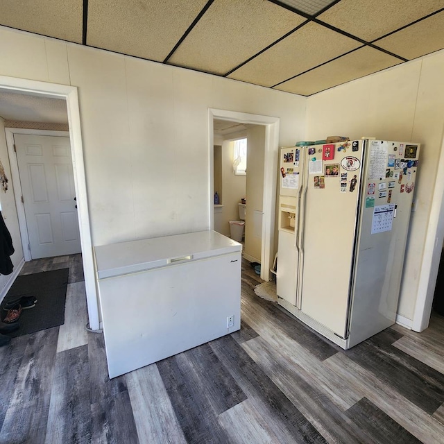 kitchen featuring light countertops, white refrigerator with ice dispenser, dark wood-style flooring, and a drop ceiling