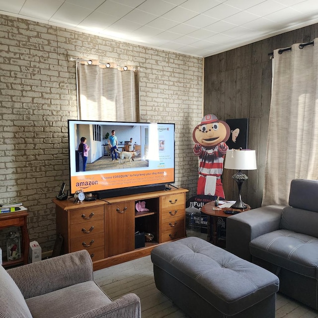 living area featuring wood finished floors and brick wall