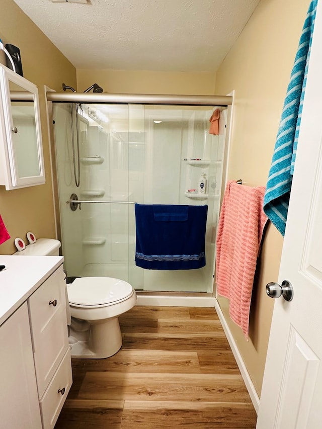 bathroom with vanity, a textured ceiling, hardwood / wood-style flooring, and toilet