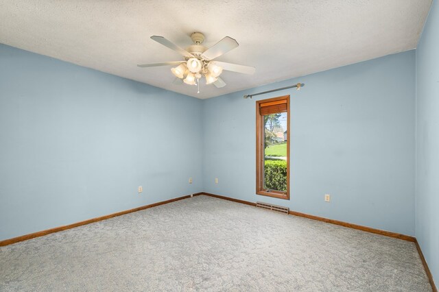 carpeted empty room with visible vents, a ceiling fan, baseboards, and a textured ceiling