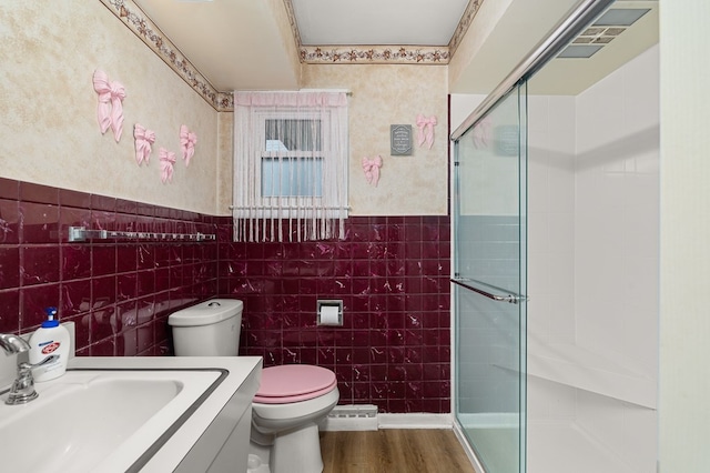 bathroom featuring an enclosed shower, tile walls, and toilet