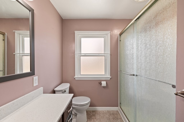 bathroom with toilet, plenty of natural light, vanity, and a shower with shower door