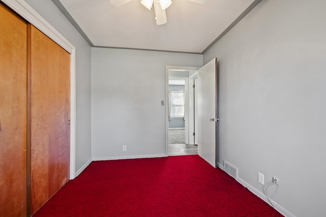 unfurnished bedroom featuring visible vents, baseboards, carpet, ornamental molding, and a closet